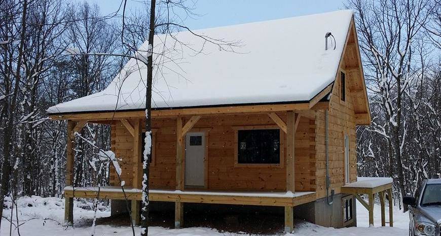 small log cabin covered with snow in the woods, log cabin, log cabin homes, log homes, log cabin kits, Timberhaven, under construction, post and beam, laminated, kiln dried, PA manufacturer