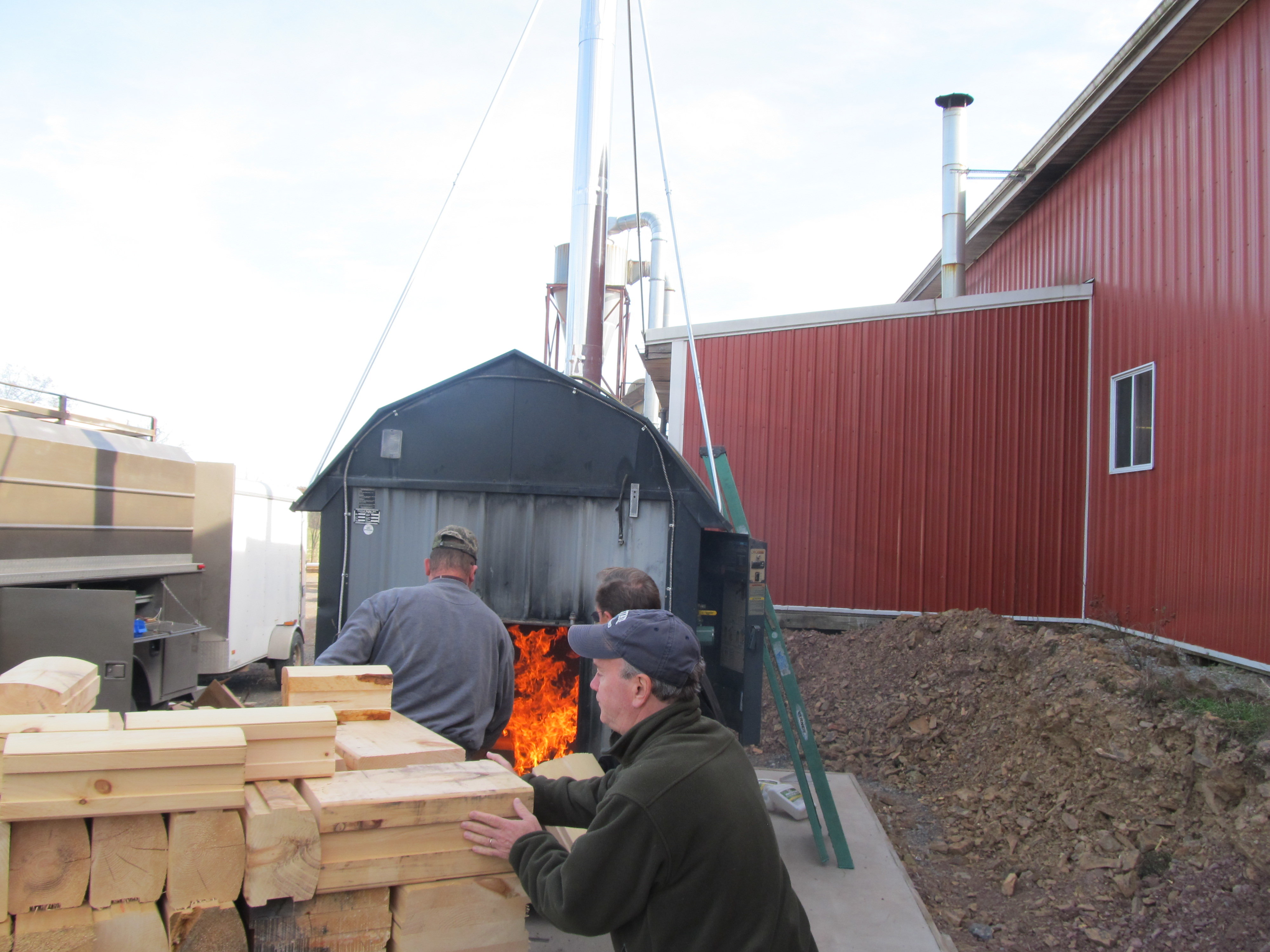 waste material being loaded into an outdoor wood burner, Timberhaven Log Homes, log homes, log cabin homes, log cabins, post and beam homes, timberframe homes, timber frame homes, laminated logs, engineered logs, floor plan designs, kiln dried logs, nature friendly