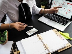 woman sitting a desk with computer and paperwork, mortgage rates on rise, log homes, timber frame homes, hybrid homes, construction loans for log homes, Timberhaven